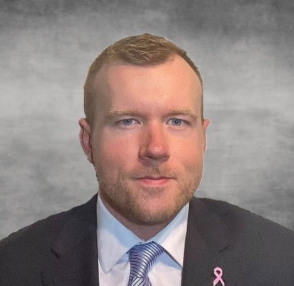 a man in a suit and tie with a pink ribbon on his lapel