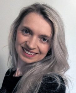 a woman with long gray hair smiling for the camera